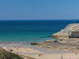 A beach with people walking and swimming near the water