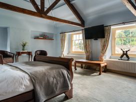 A bedroom with a bed, chairs, and a television at The Meeting House in Ashburton