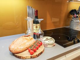 A kitchen counter with bread, wine, glasses, tomatoes, and cheese at Premier, Transit & Lady Hilda @ Engine Shed in Whitby