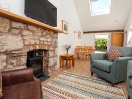 A living room with a stone fireplace a wood stove two armchairs a wooden dining table with four chairs and a skylight at Bwthyn Taid in Holywell