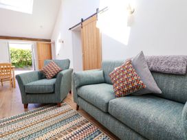A living room with a blue sofa and armchair with patterned cushions wooden doors and a dining table visible at Bwthyn Taid in Holywell