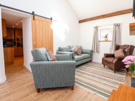 A living room with two blue sofas a brown armchair a patterned rug and a sliding wooden door at Bwthyn Taid in Holywell