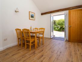 A dining area with wooden table and chairs near open glass doors leading outside at Bwthyn Taid in Holywell