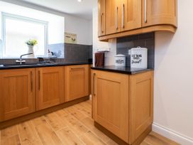 A kitchen with wooden cabinets black countertops a window and containers for biscuits and bread at Bwthyn Taid in Holywell
