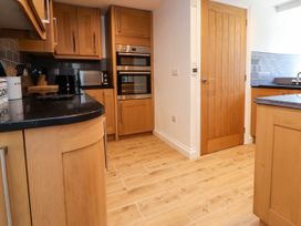 A kitchen with wooden cabinets black countertops a microwave double oven and a wooden door at Bwthyn Taid in Holywell