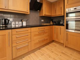A kitchen with wooden cabinets a black countertop a kettle and canisters labeled tea sugar and coffee at Bwthyn Taid in Holywell