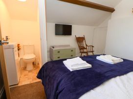 A bedroom with a bed and folded towels a wall-mounted TV a wooden chair and an adjacent bathroom at Bwthyn Taid in Holywell