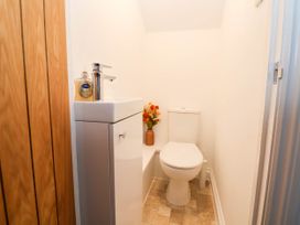 A small bathroom with a toilet sink with hand soap and flowers on a shelf at Bwthyn Taid in Holywell