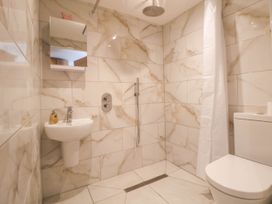 A bathroom with a wall-mounted sink mirror shower curtain and toilet at Bwthyn Taid in Holywell