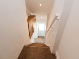 Carpeted staircase with white walls a wooden cabinet on the left and a white door at the bottom at Bwthyn Taid in Holywell