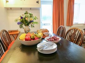 A dining table with fruit, cheese, bread, and flowers at Ael Y Bryn in Menai Bridge