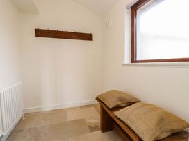 A hallway with coat hooks, a bench, and a radiator at Bryn Deryn in Criccieth