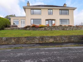 A house with a stone wall and lawn at Bryn Deryn in Criccieth