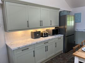 A kitchen with cabinets, refrigerator, microwave, and toaster at Bryn Eira Stables in Llanfair PG
