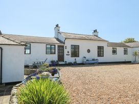 A white house with dark framed windows and a gravel courtyard at Borth Arian in Rhoscolyn