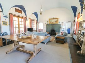 A living room with wooden table blue sofas fireplace and arched ceiling at Borth Arian in Rhoscolyn