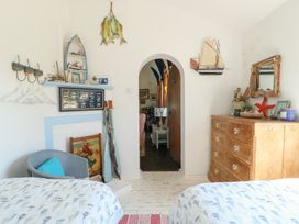 A bedroom with two beds a wooden dresser and nautical decorations at Borth Arian in Rhoscolyn