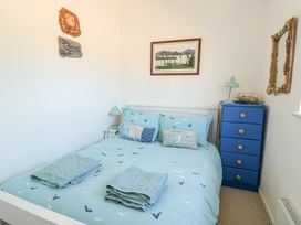 A bedroom with a bed with blue bedding and towels on it a blue chest of drawers and wall decorations at Borth Arian in Rhoscolyn