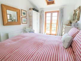 A bedroom with red and white striped bed linen a wooden framed mirror white wardrobe and wooden double doors at Borth Arian in Rhoscolyn