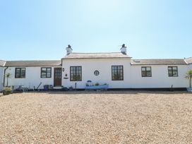 A white single-story house with multiple windows and a gravel yard at Borth Arian in Rhoscolyn