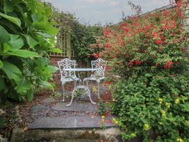 A garden with a table and chairs surrounded by plants at Y Bwthyn in Criccieth