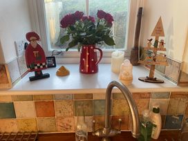A kitchen counter with a kettle flowers and Christmas decorations at Cae'r Dyni (Caer Dyni) Criccieth
