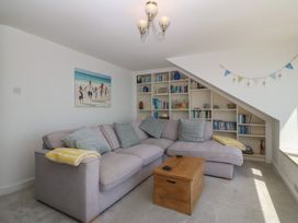 A living room with a sofa and bookshelves at Captain's Rest in Criccieth
