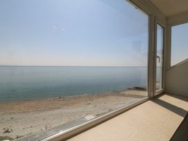 A view from a window overlooking the sea and beach at Captain's Rest in Criccieth
