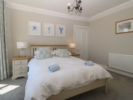 A bedroom with a large bed and bedside lamps at Captain's Rest in Criccieth