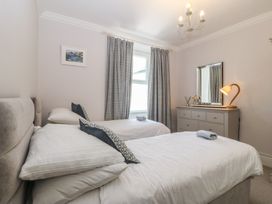 A bedroom with two single beds and a chest of drawers at Captain's Rest in Criccieth