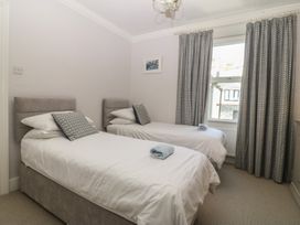 A bedroom with two single beds and a window at Captain's Rest in Criccieth