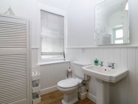 A bathroom with a sink, toilet, and mirror at Captain's Rest in Criccieth