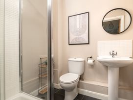 A bathroom featuring a shower, toilet, sink, and wall art at Coed y Felin in Conwy