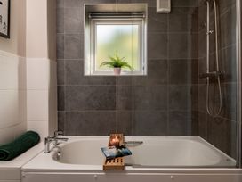 A bathtub with a shower and window at Coed y Felin in Conwy