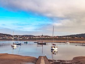 A view of boats on water with a pier and houses in the background at Coed y Felin in Conwy