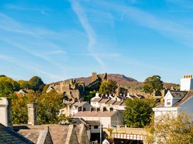 A view of rooftops with a castle and mountains at Coed y Felin Conwy