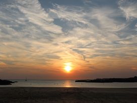 A sunset over the ocean with clouds at Curragho in Trearddur Bay