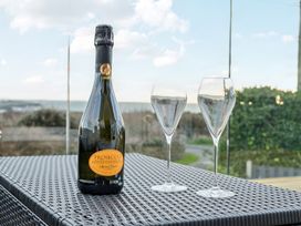A bottle of prosecco and two champagne flutes on a table with an outdoor view at Curragho in Trearddur Bay