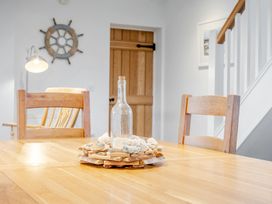 A dining room with a wooden table and chairs at Curragho in Trearddur Bay