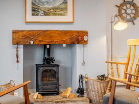 A living room with a fireplace and rocking chair at Curragho Trearddur Bay