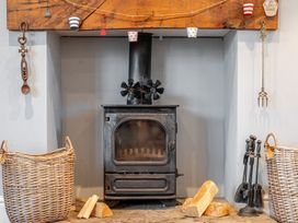 A living room with a wood stove and baskets at Curragho in Trearddur Bay