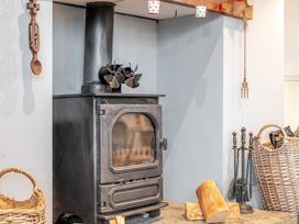 A stove with firewood beside it at Curragho in Trearddur Bay