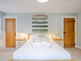 A bedroom with a bed, side tables, and lamps at Curragho in Trearddur Bay