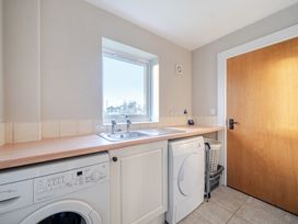 A utility room with a washing machine and sink at Curragho in Trearddur Bay