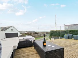An outdoor space with seating and a bottle of wine at Curragho in Trearddur Bay