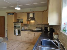 A kitchen with cabinets, stove, oven, sink, and small appliances at Bryn Eira Tack Room Llanfair PG