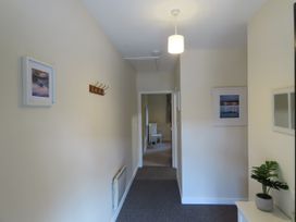 A hallway with coat hooks and framed pictures at Bryn Eira Tack Room in Llanfair PG