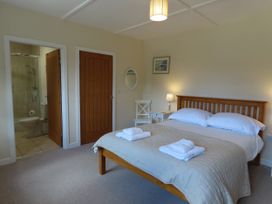 A bedroom with a bed and bathroom access at Bryn Eira Tack Room Llanfair PG