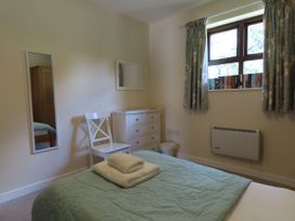 A bedroom with a bed a chair and a dresser at Bryn Eira Tack Room in Llanfair PG