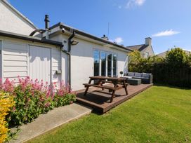 A house with a patio and flowerbed at Farm Cottage in Cemaes Bay